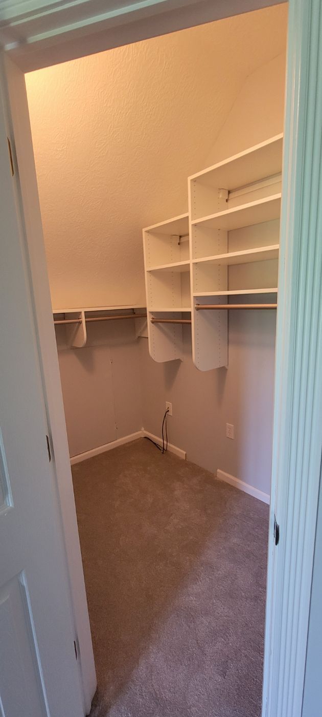 a walk in closet with lots of shelves and a door .