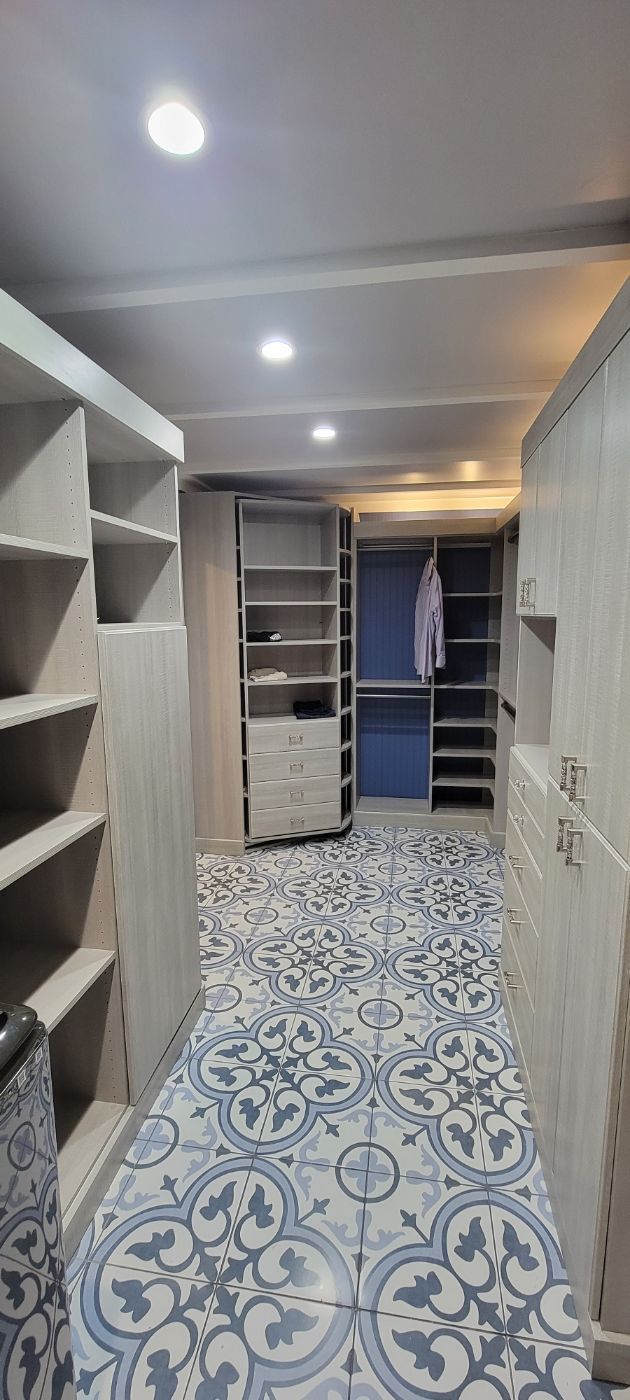 a walk in closet with lots of shelves and a tiled floor .