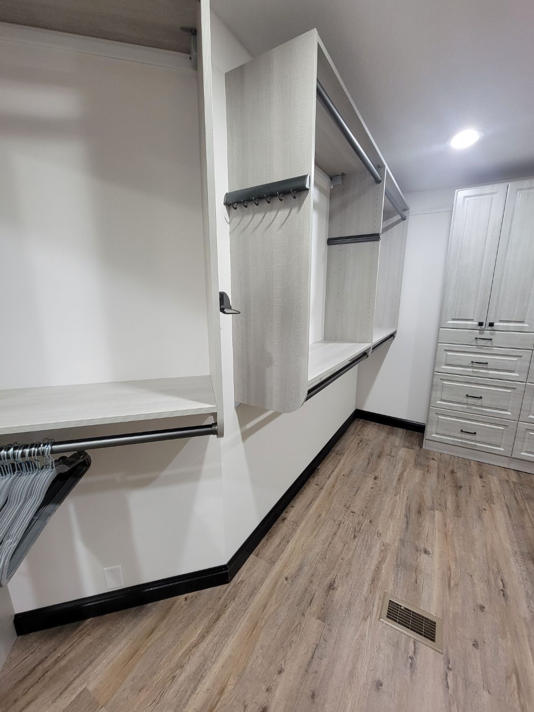a walk in closet with hardwood floors and white walls .