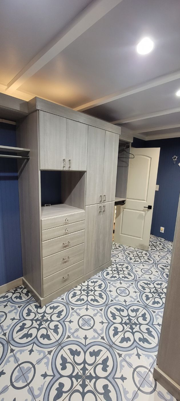 a walk in closet with lots of cabinets and drawers and a tiled floor .