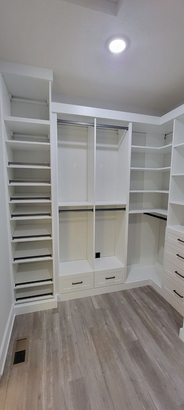 a walk in closet with lots of shelves and drawers .