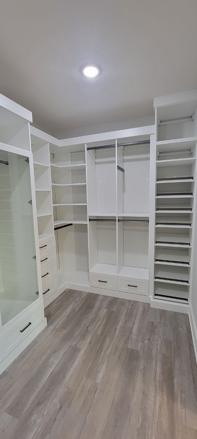 a large walk in closet with lots of shelves and drawers .