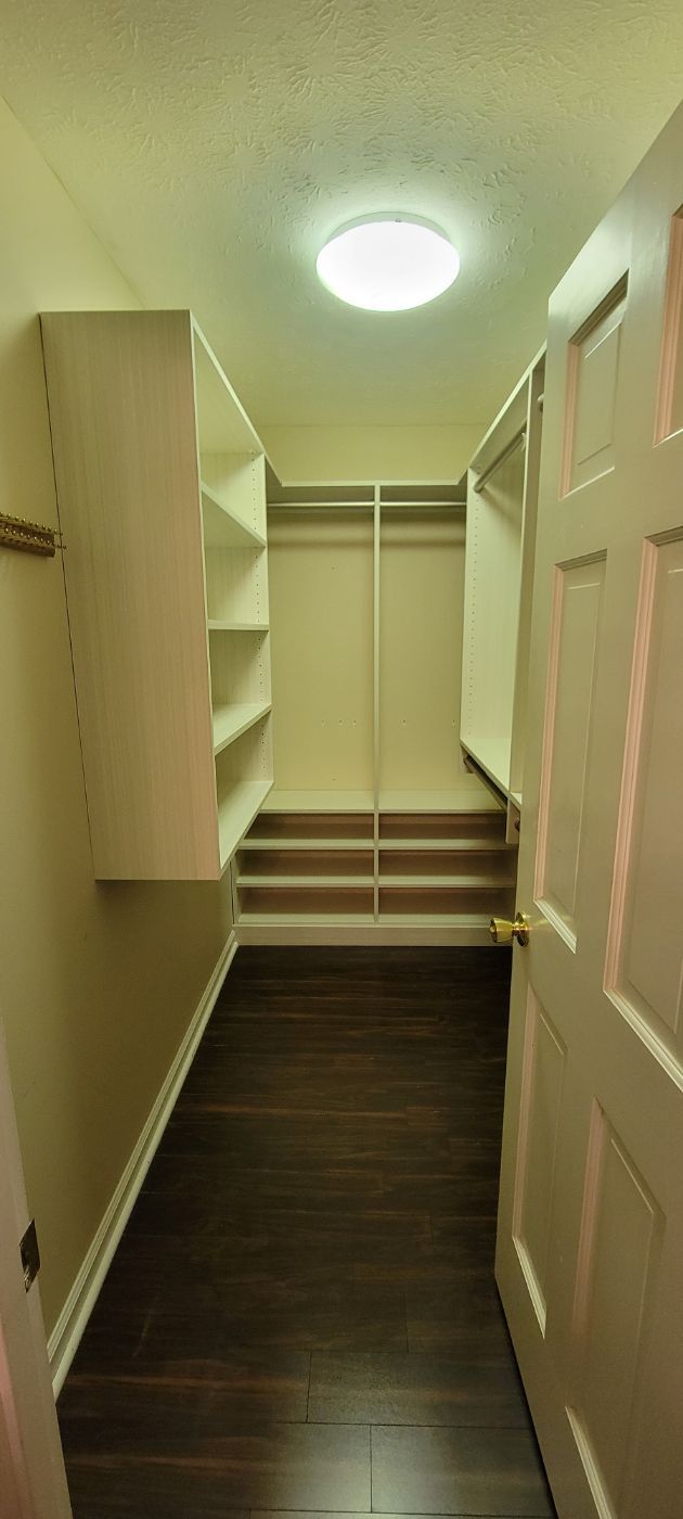 a walk in closet with lots of shelves and a door .