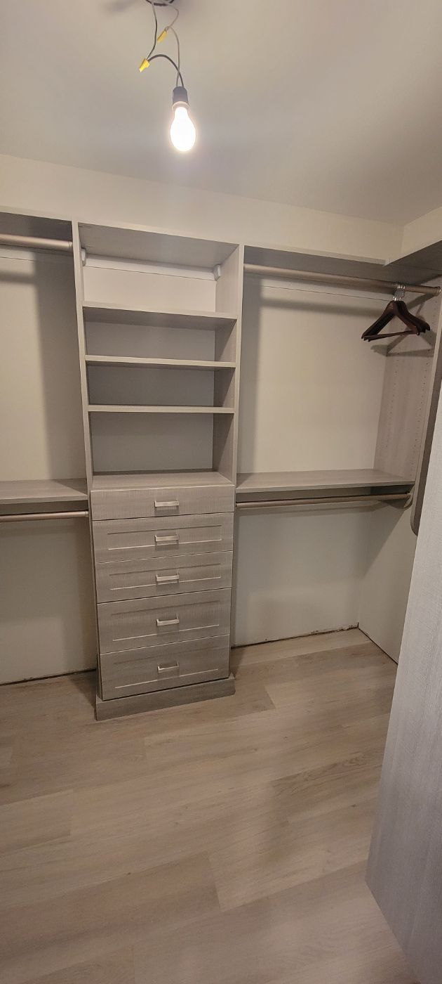 a walk in closet with lots of shelves and drawers .