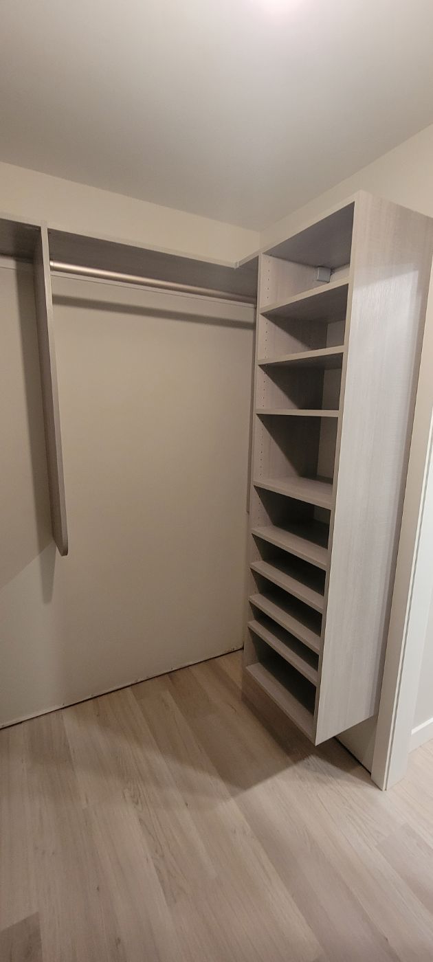a walk in closet with lots of shelves and clothes racks .