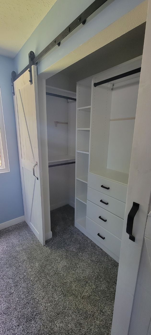 a walk in closet with sliding barn doors in a bedroom .