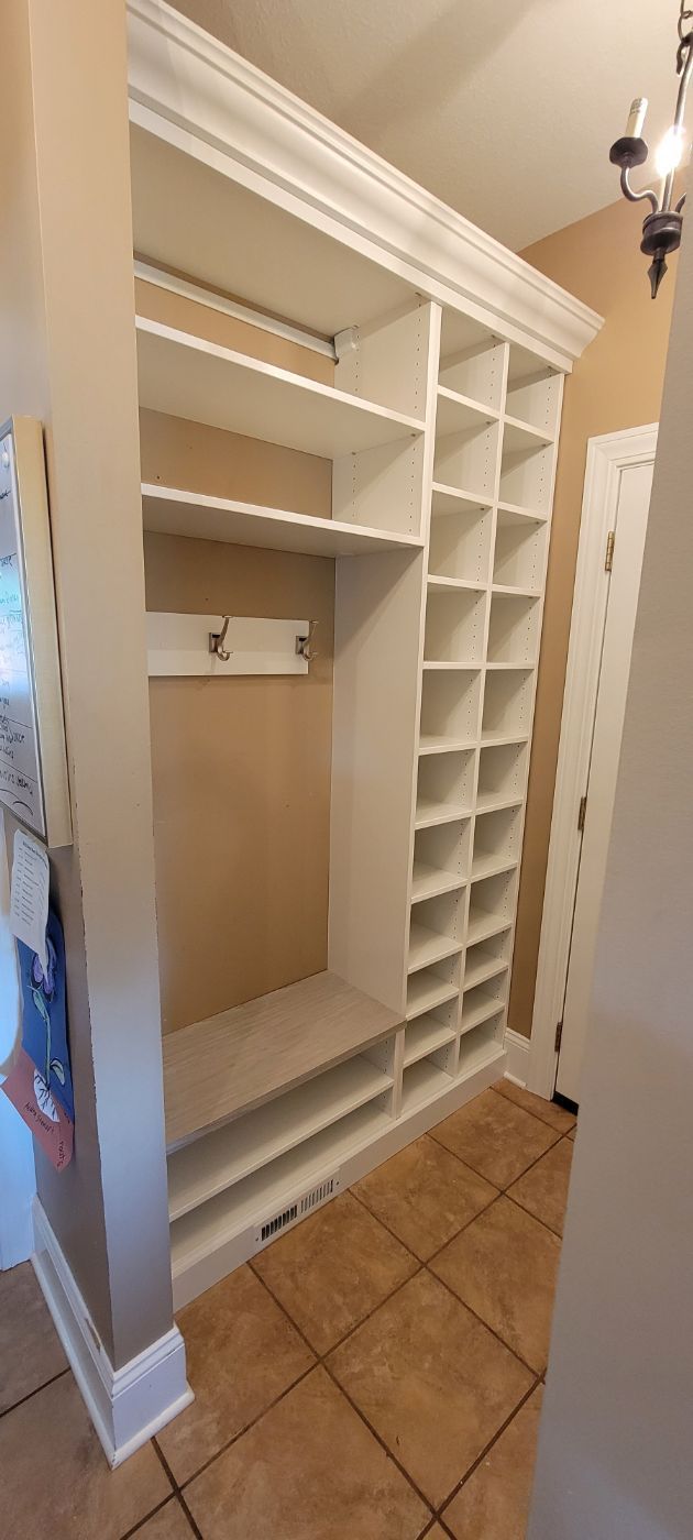 a walk in closet with lots of shelves and a bench .