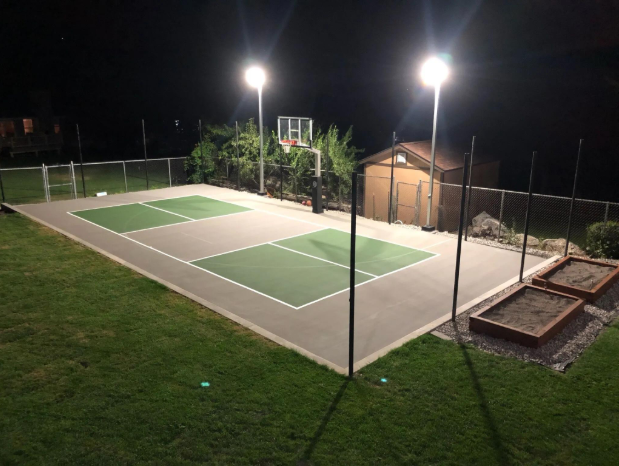 Outdoor sport court lit by tall lights at night with green and gray playing areas after a court installation service in San Tan Valley, AZ