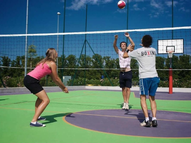 Players jumping to hit a volleyball over a net on a colorful outdoor court during a court installation service in San Tan Valley, AZ