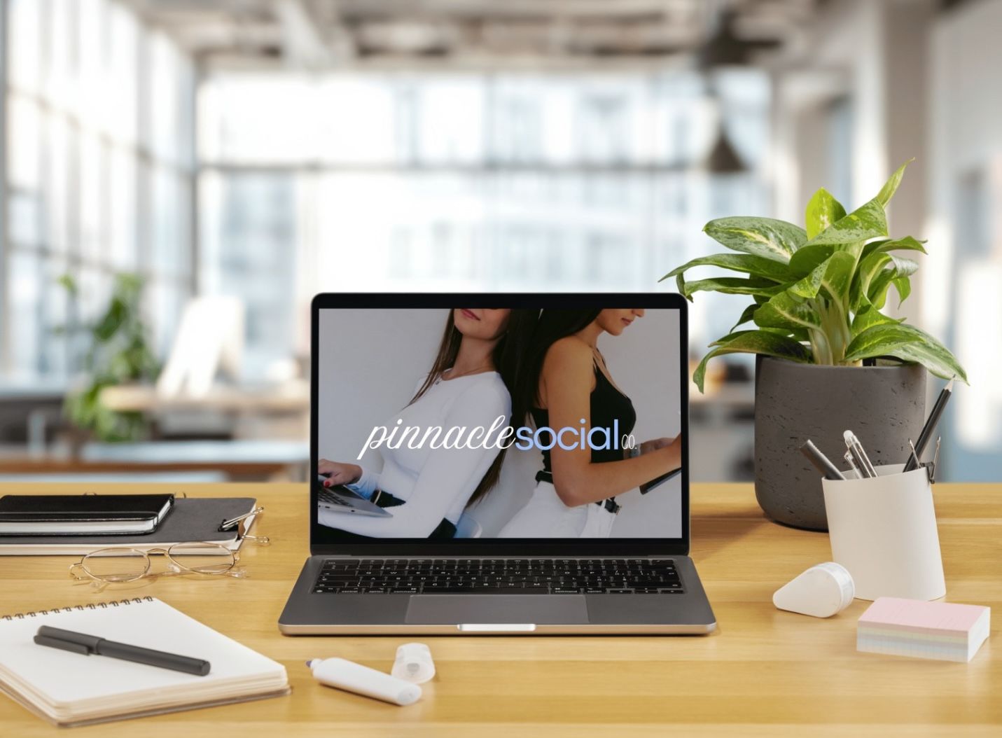 A laptop on a wooden desk displaying the logo 
