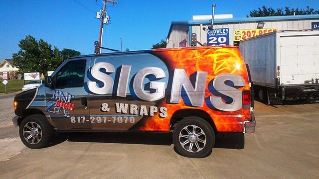 A signs and wraps van is parked in a parking lot