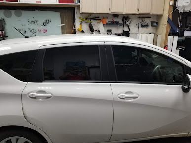 A white car with black windows is parked in a garage.