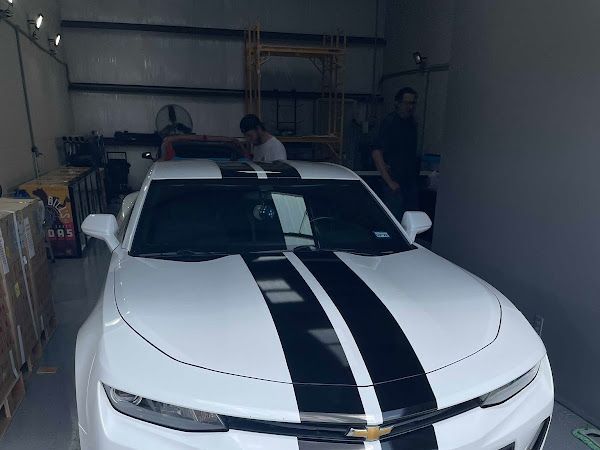 A white car with black stripes is parked in a garage.