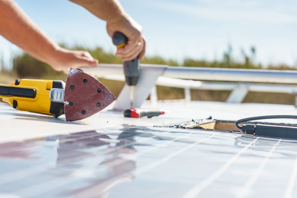 A Person Is Working on A Solar Panel with A Drill and Sander — Ryde Energy in Ipswich, QLD