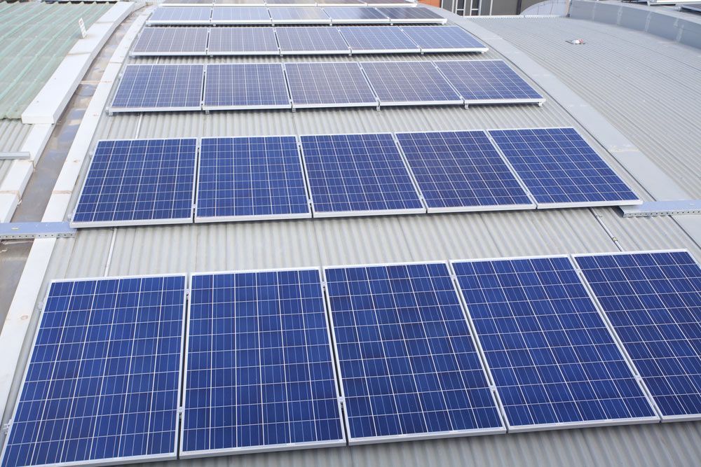 A Row of Solar Panels on The Roof of A Building — Ryde Energy in Browns Plains, QLD