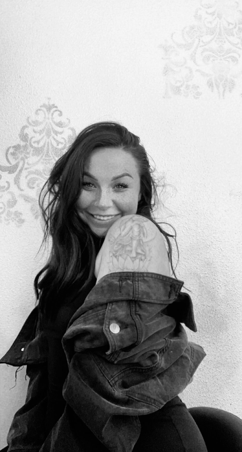 A woman in a plaid shirt is taking a selfie in a black and white photo.