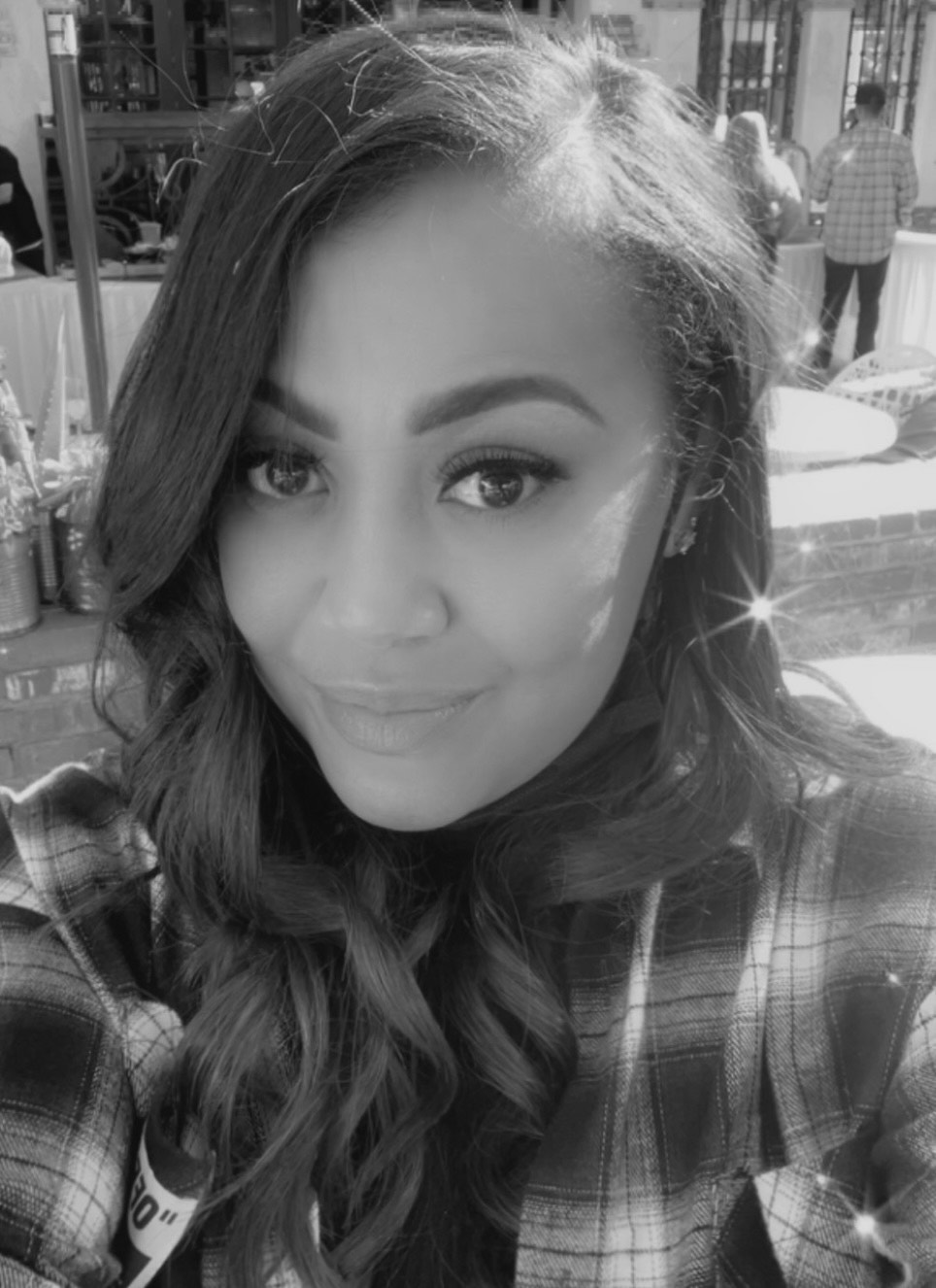 A woman in a plaid shirt is taking a selfie in a black and white photo.