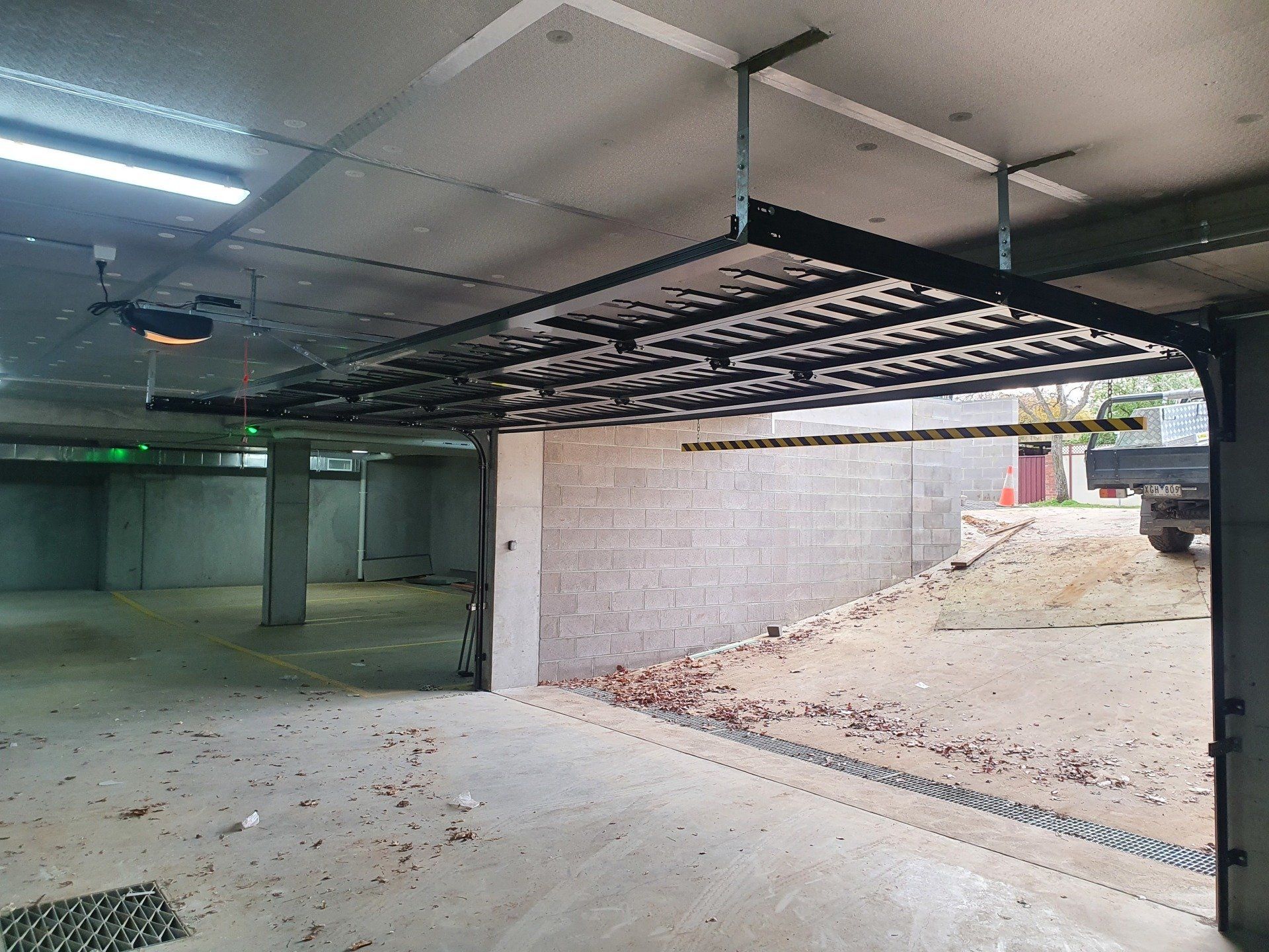 A garage with a garage door open and a truck parked in the background.