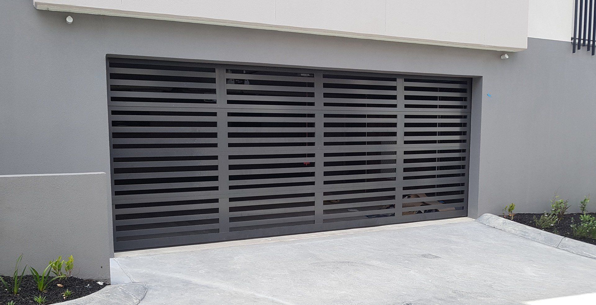 A black garage door is open in front of a building.