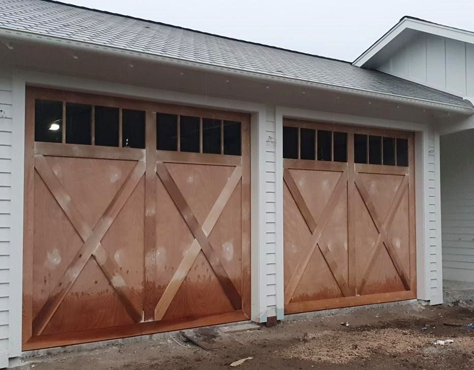 A white house with two wooden garage doors