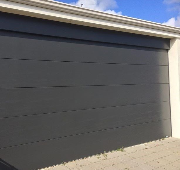 A gray garage door with a white trim and a blue sky in the background