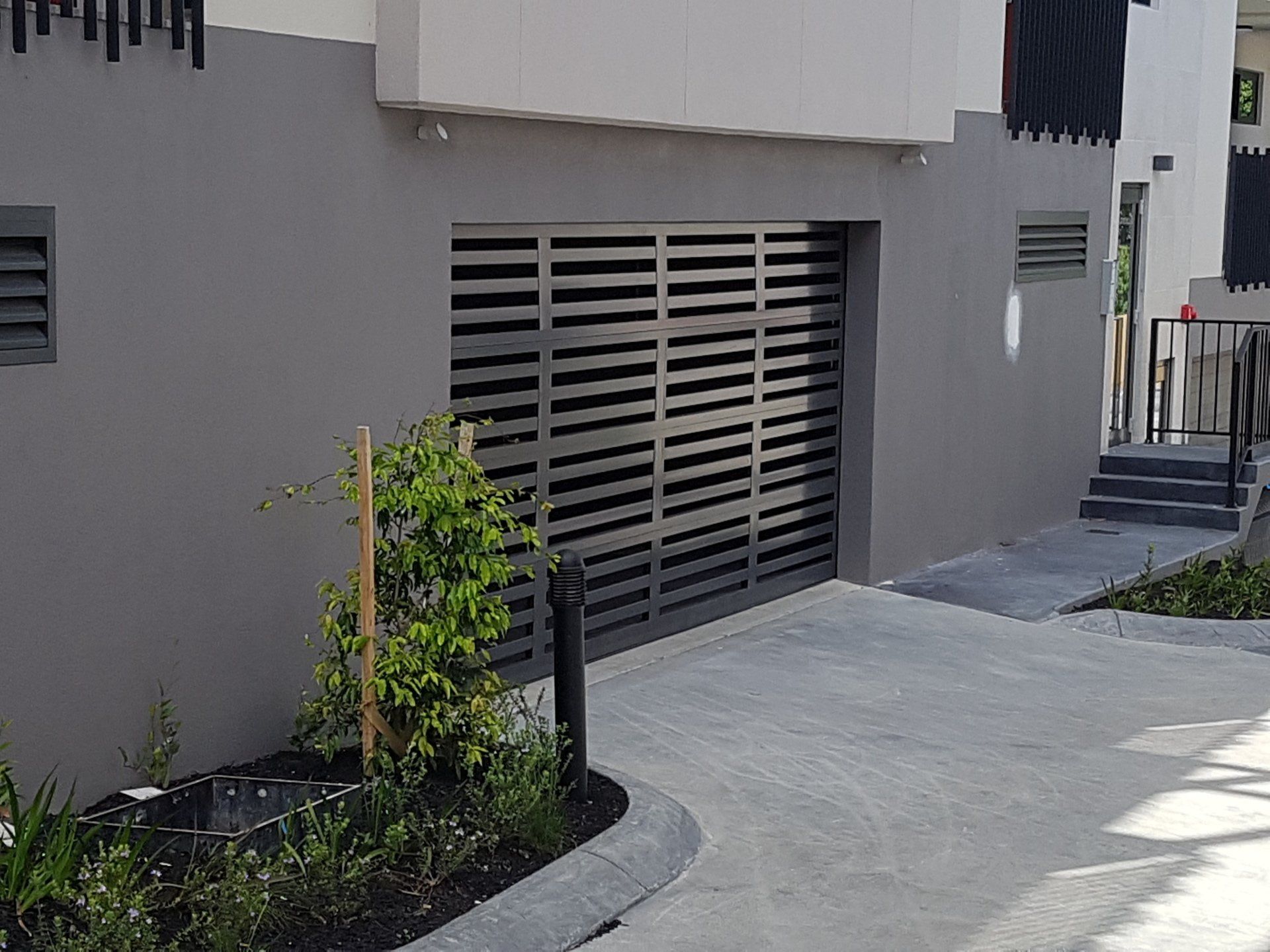 A building with a sliding garage door and a concrete driveway