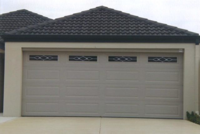 A garage door is open in front of a house with a black roof.