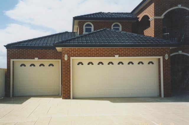 A large brick house with three white garage doors