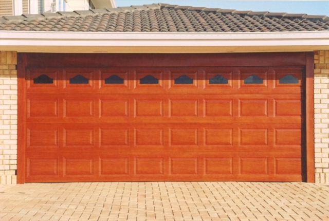 A wooden garage door is open in front of a brick house