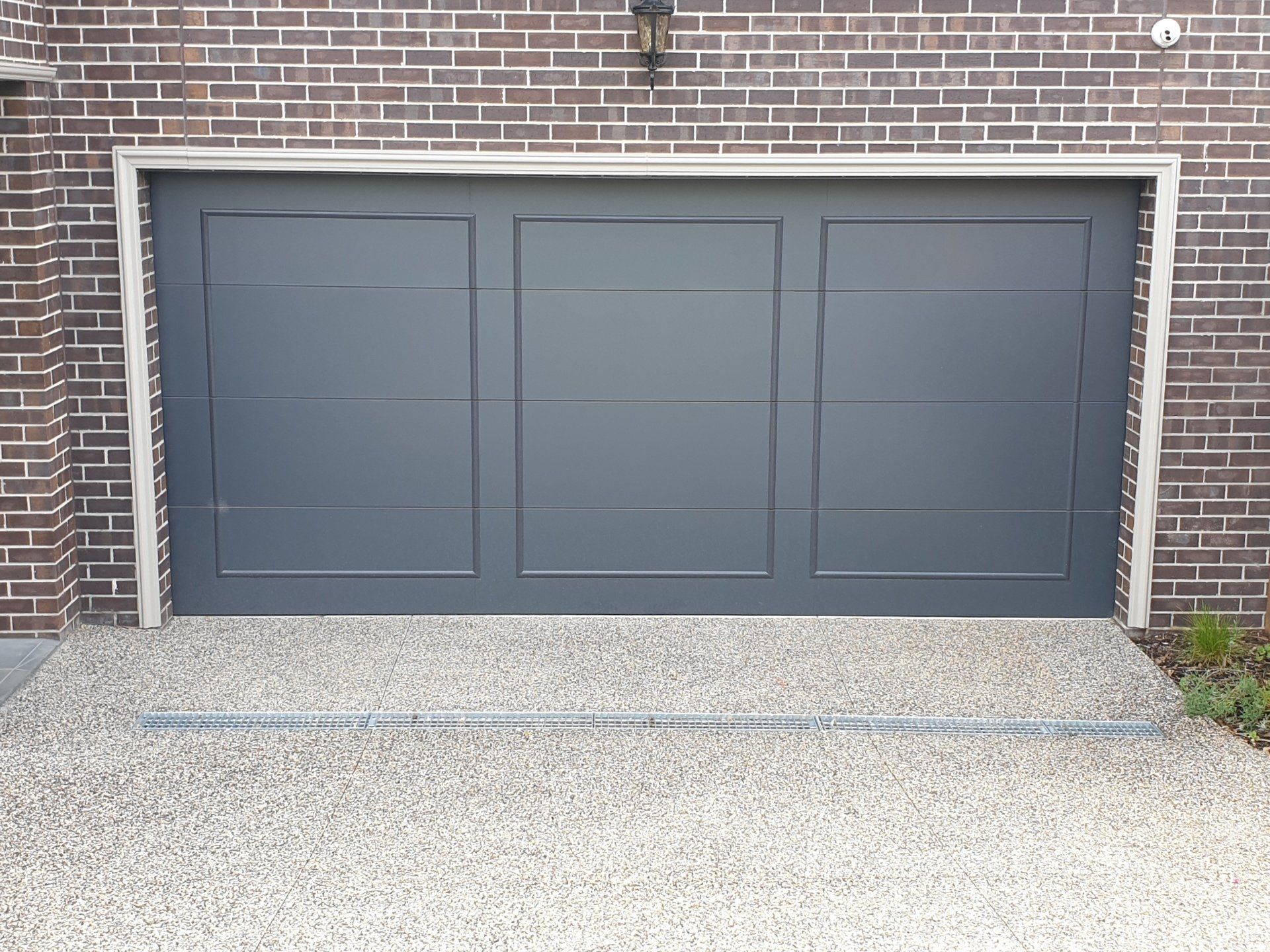 A black garage door is sitting in front of a brick building.