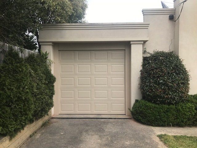 A white garage door is open in front of a house.