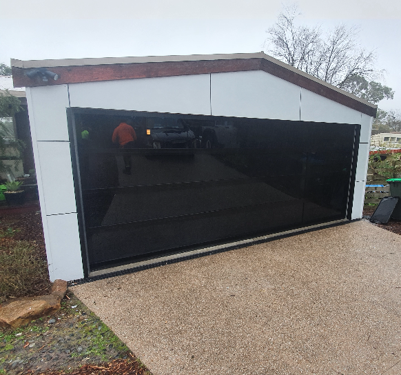 A car is parked in a garage with a black garage door.