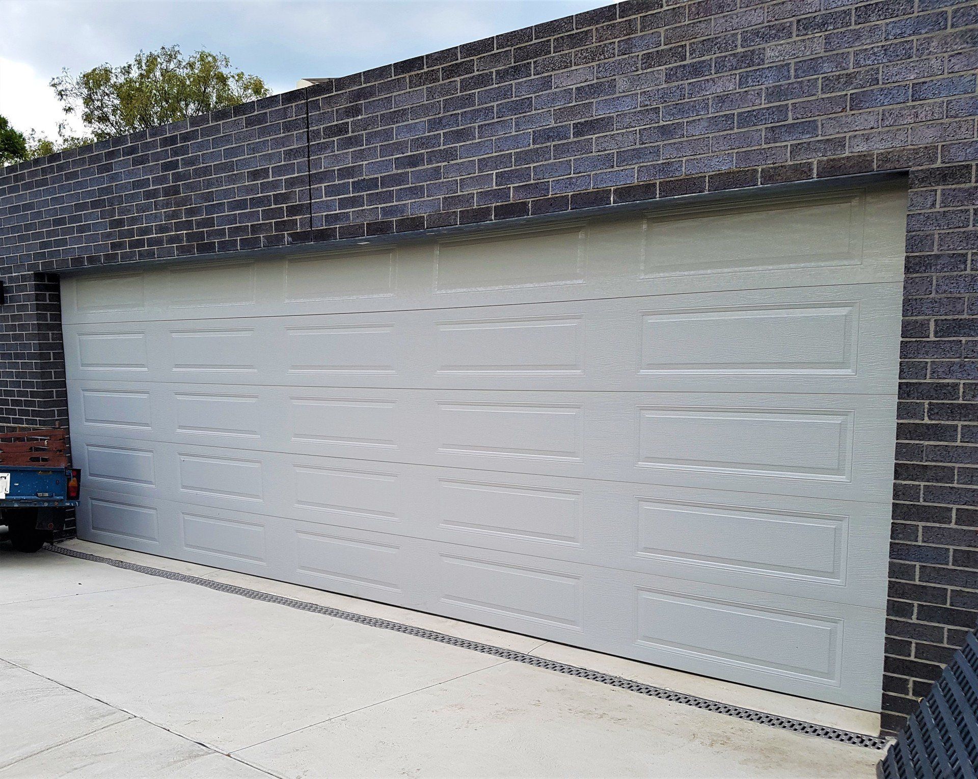 A white garage door is against a blue brick wall