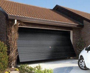 A white car is parked in front of a garage door that is open
