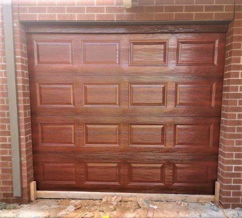 A wooden garage door is sitting on top of a brick wall.