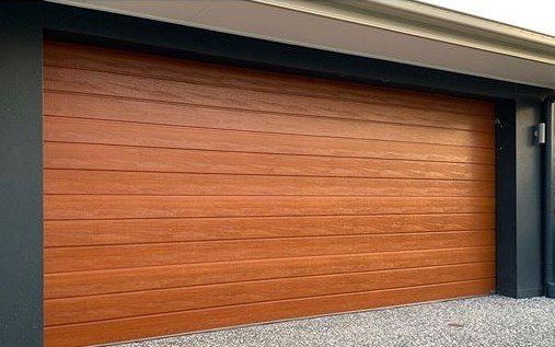 A wooden garage door is sitting in front of a house.