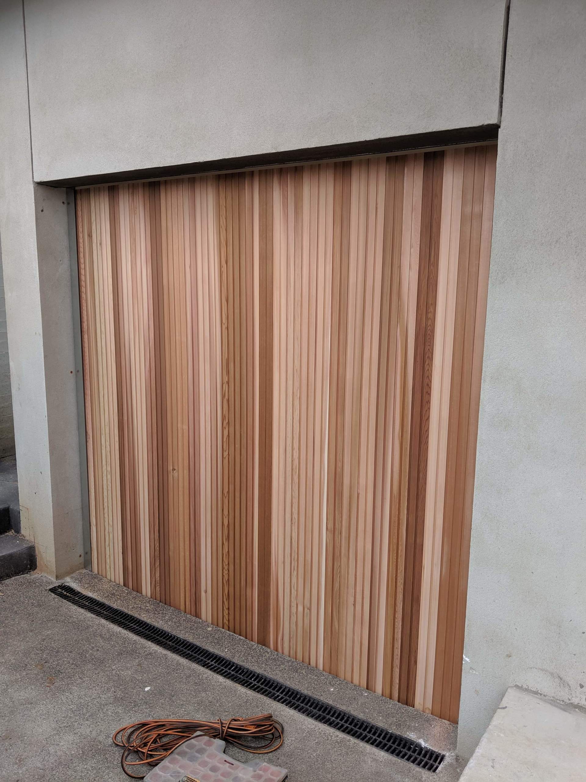 A wooden garage door is sitting on the side of a building.
