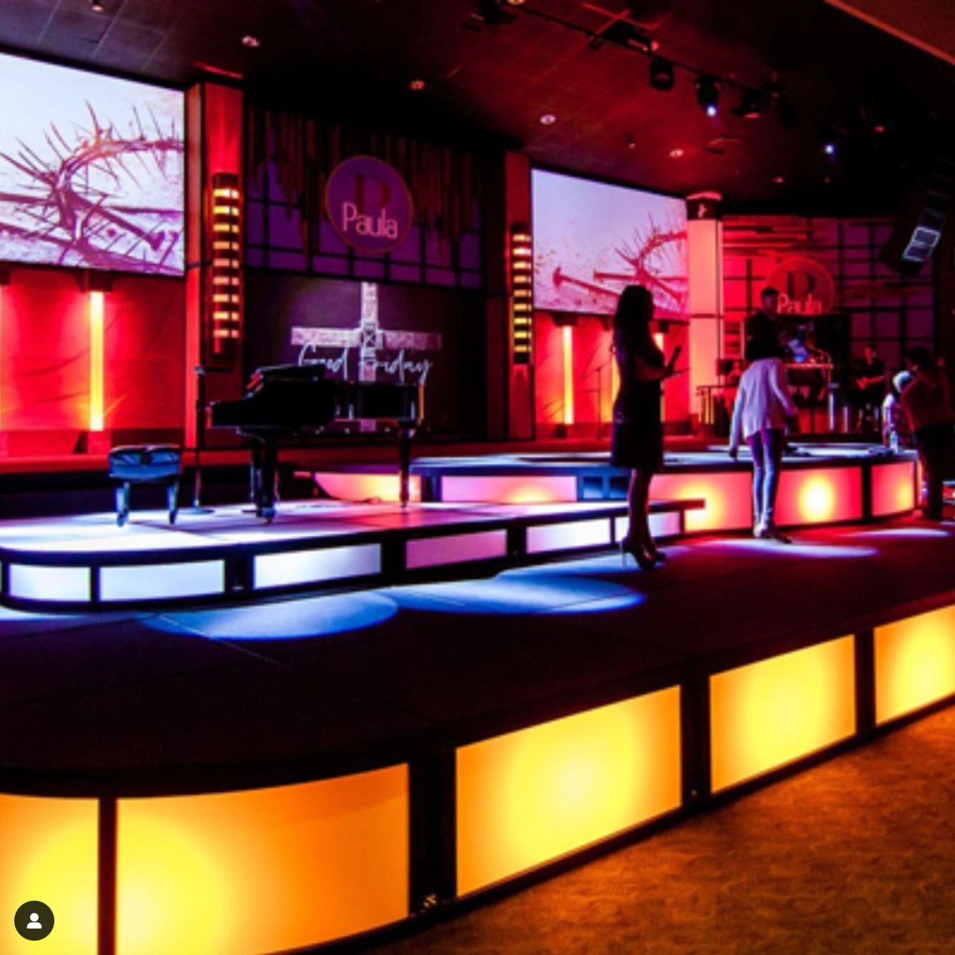 A woman stands on a stage in front of a sign that says paula