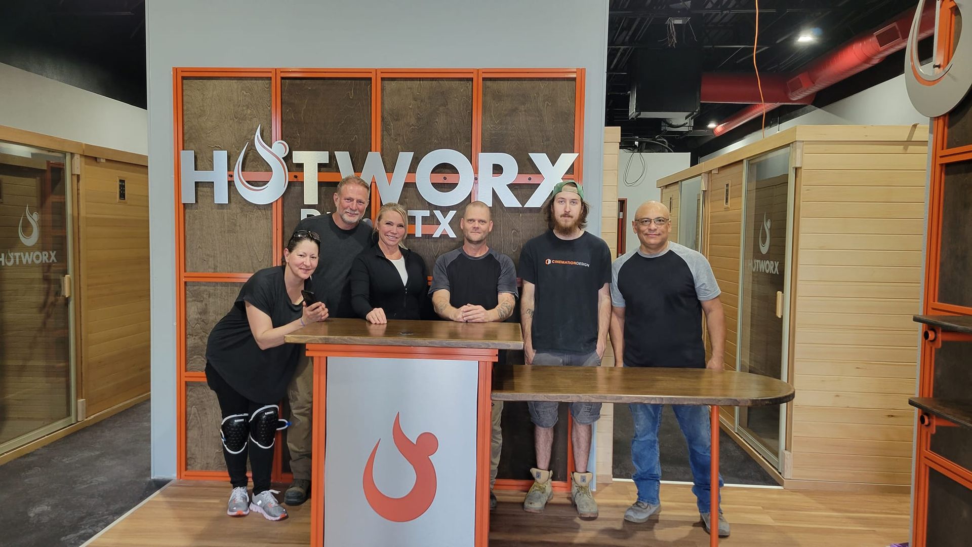 A group of people are posing for a picture in front of a sign that says hotwork.