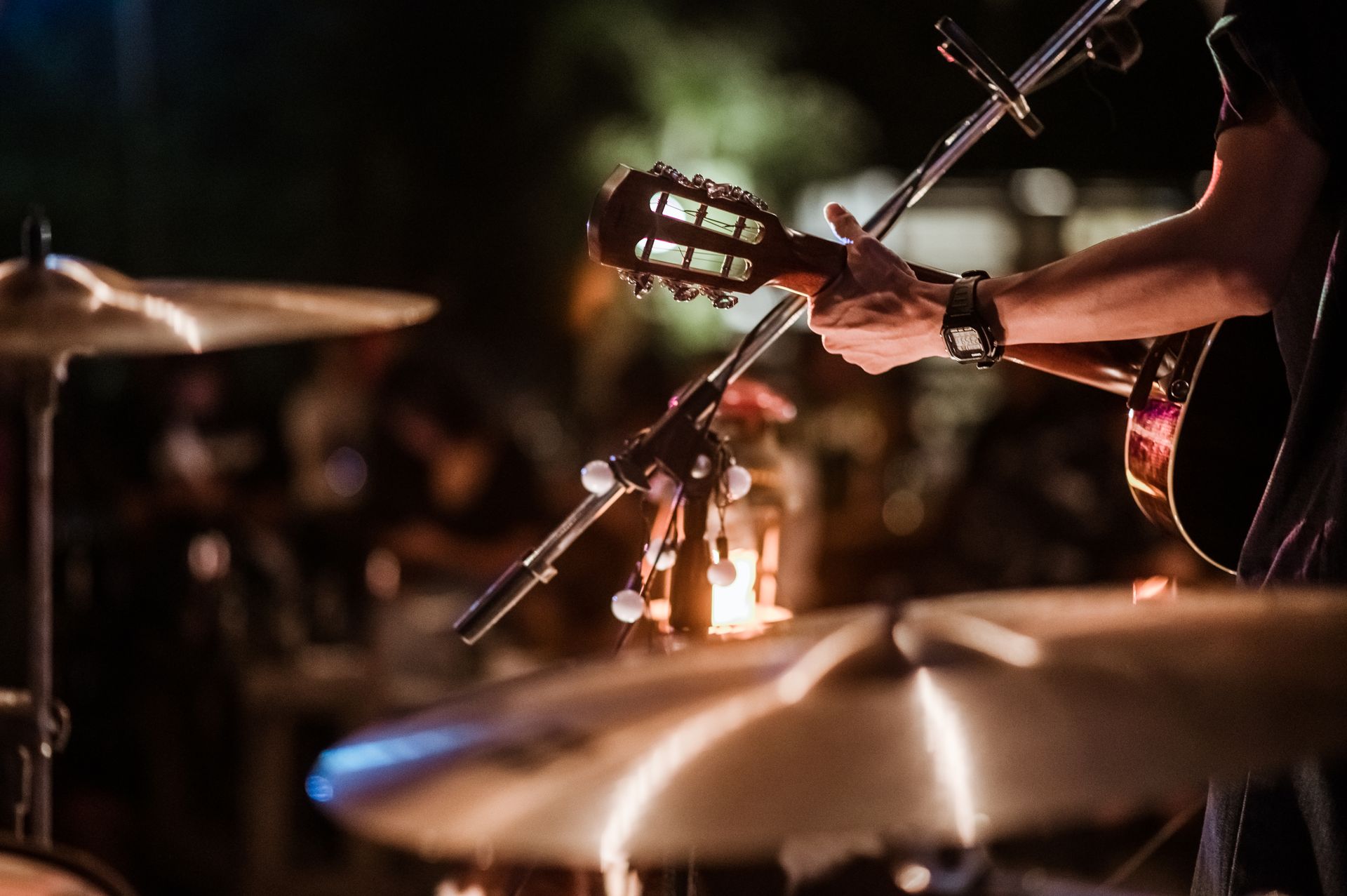 A man is playing a guitar and drums on a stage.