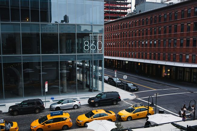 A row of yellow taxis are parked on the side of a city street.
