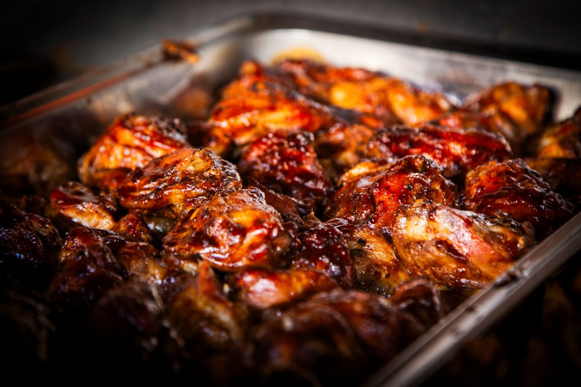 Tray of glazed, browned chicken pieces.