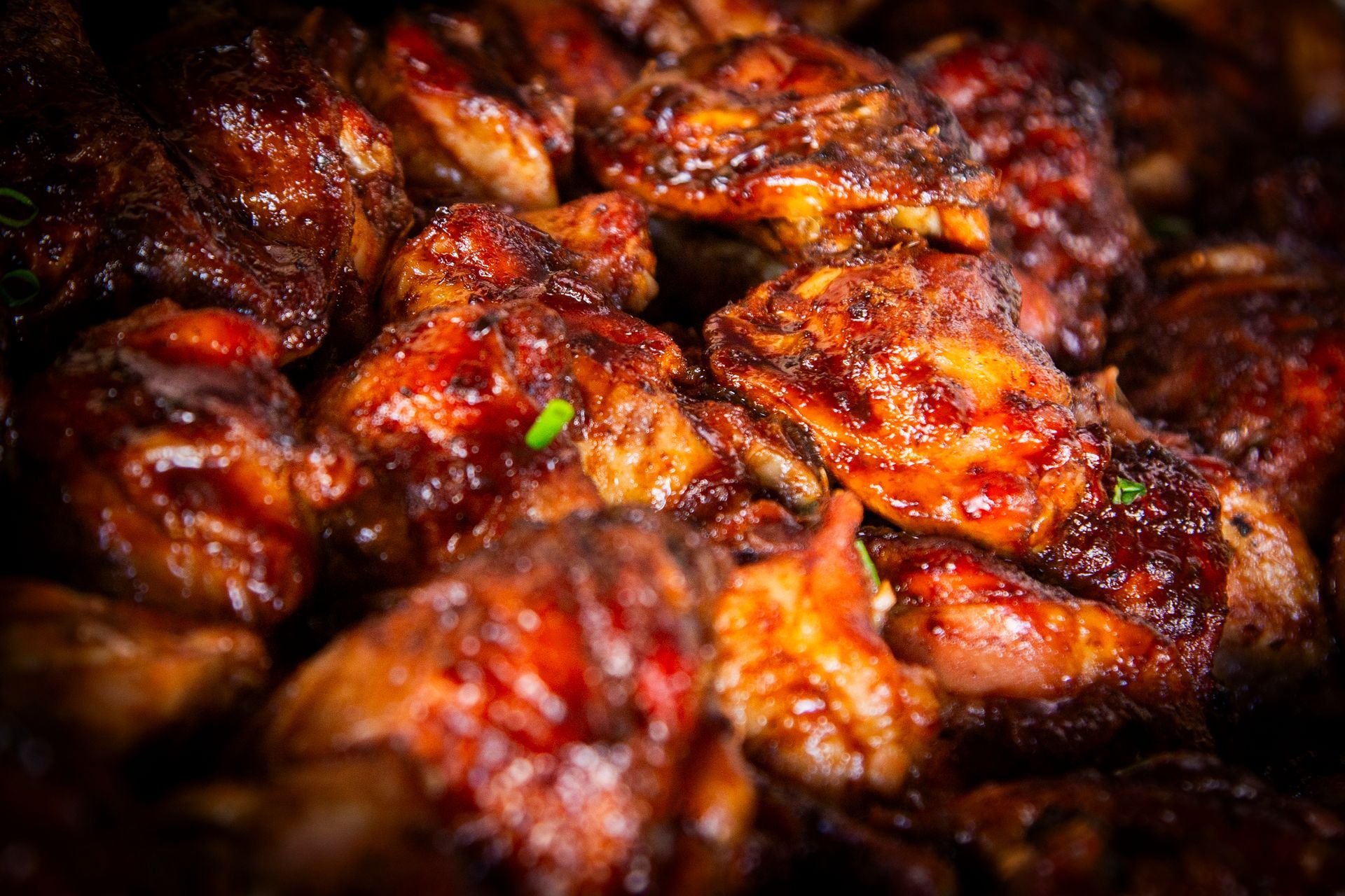 Close-up of glazed chicken pieces, with glossy dark-brown sauce; warm, rich colors.