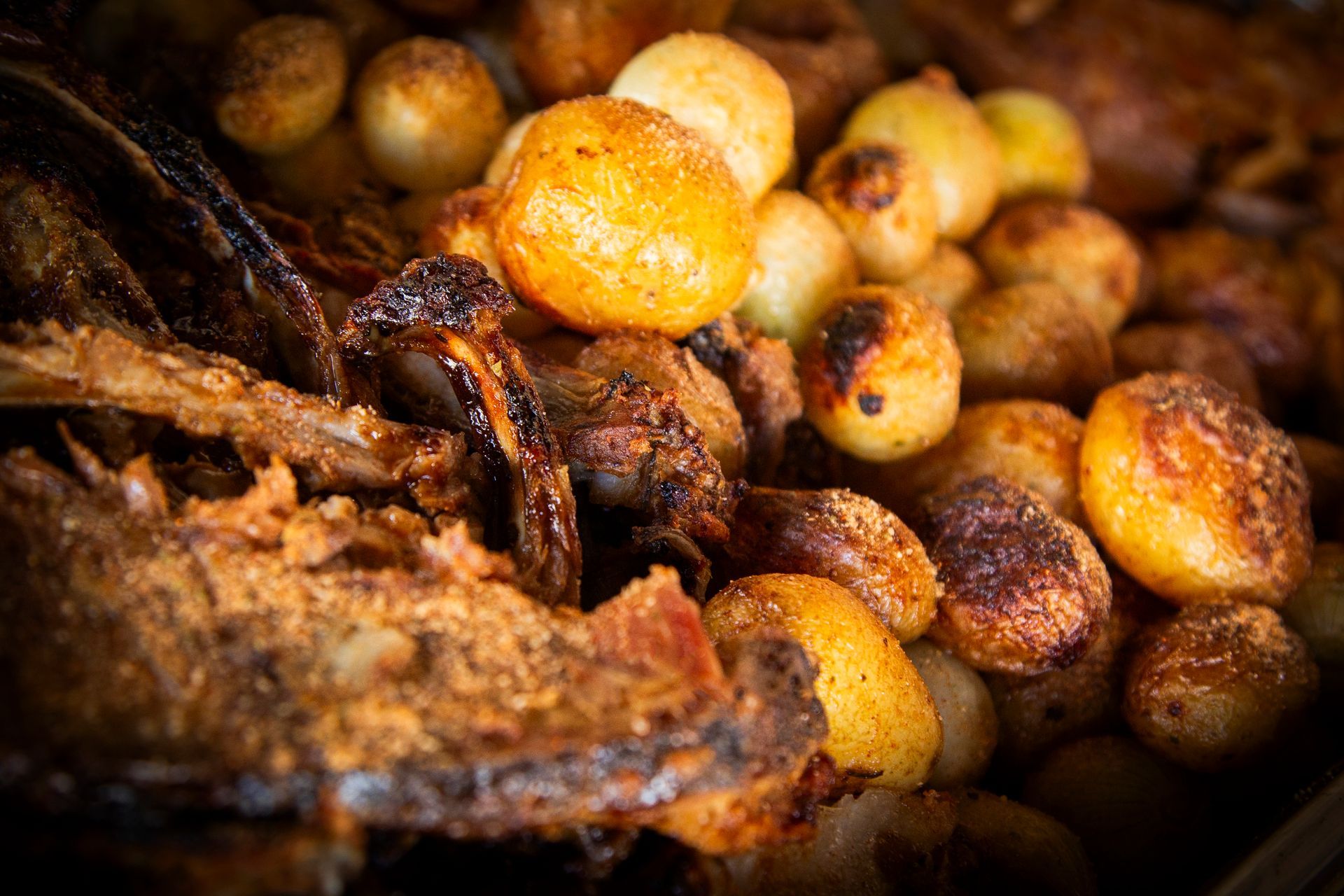 Roasted potatoes and meat, golden brown, close-up view.