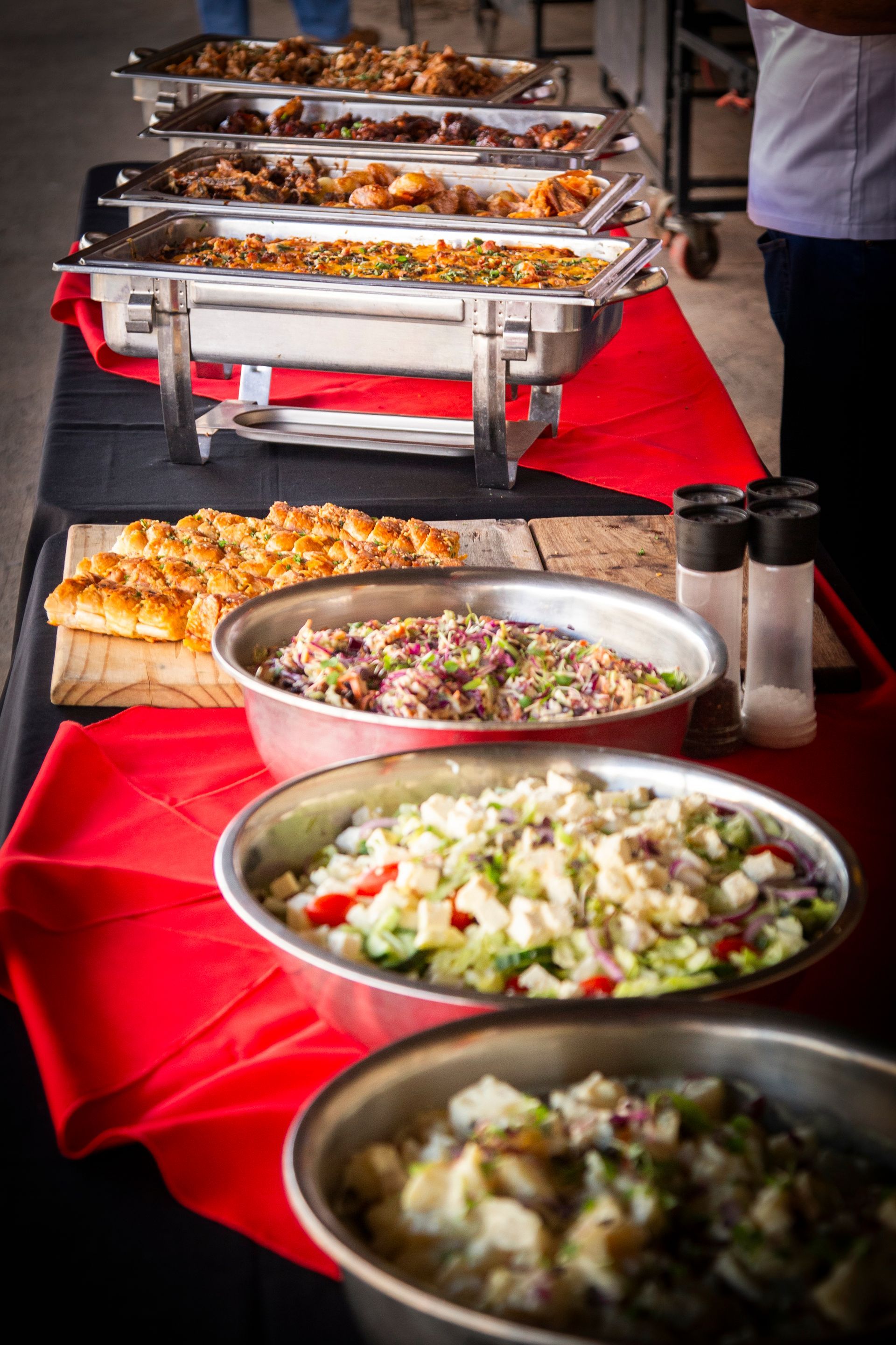 Buffet with various dishes, salads, and bread, set on a table with red tablecloth.