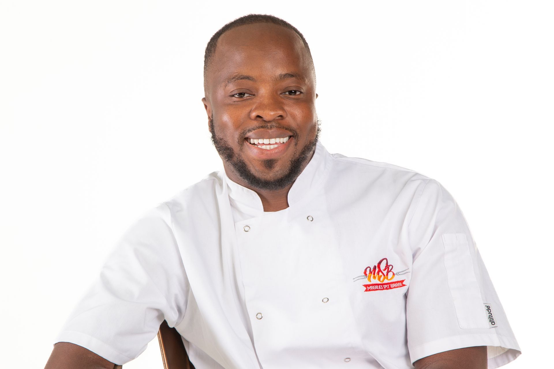 Chef smiling, wearing a white chef's coat. Has a short beard.