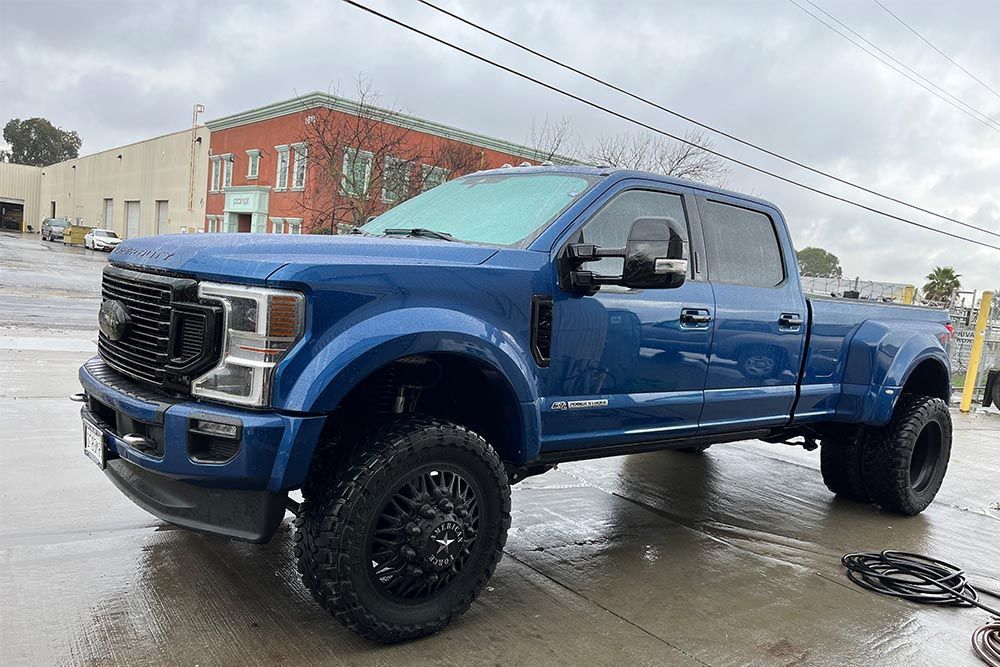 A blue pickup truck is parked in a parking lot in front of a building.
