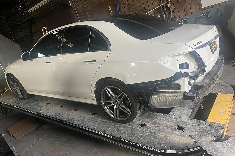 A white car is sitting on top of a tow truck.