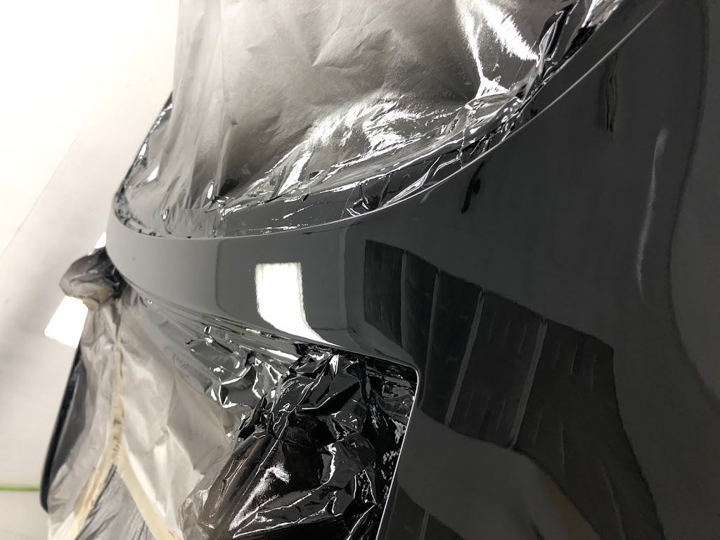 A car is wrapped in plastic and being painted.