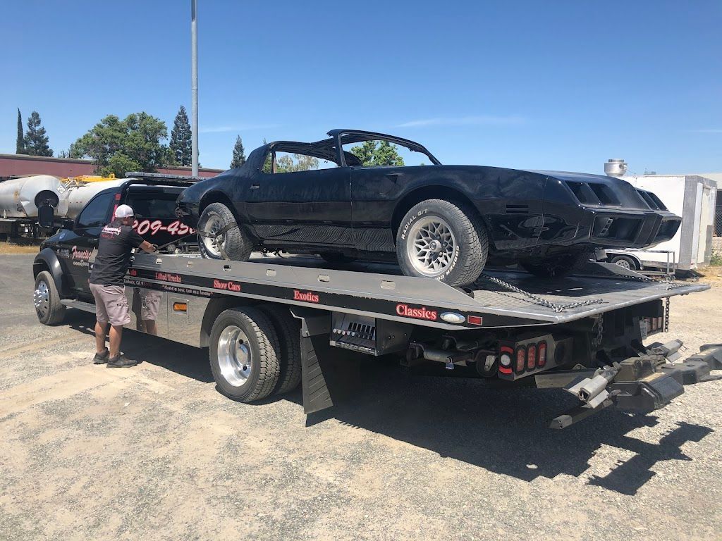 A black car is being towed by a tow truck.